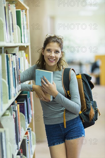 Mixed Race girl holding book in library