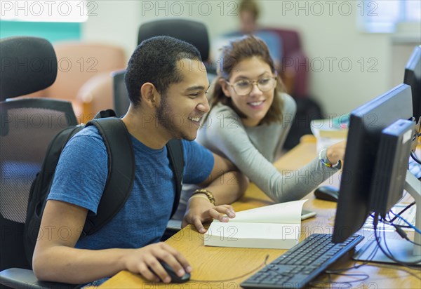 Mixed Race boy and girl using computer in library