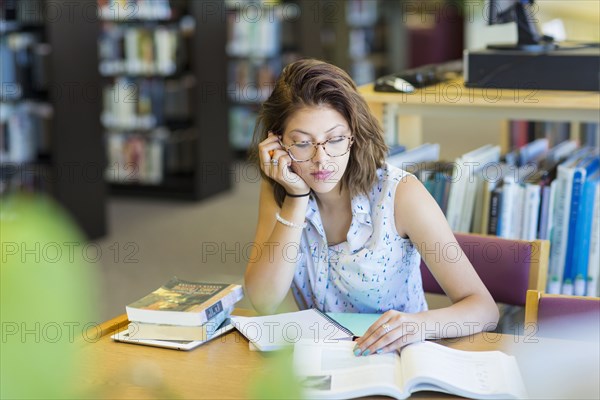 Mixed Race girl reading book in library