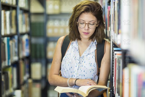 Mixed Race girl reading book in library