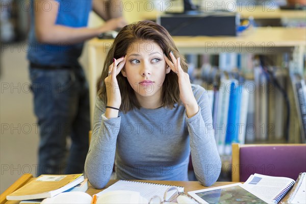 Mixed Race girl rubbing temples in library