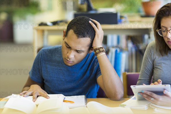 Mixed Race boy reading book in library