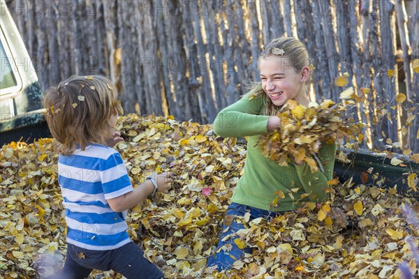 Caucasian brother and sister throwing autumn leaves