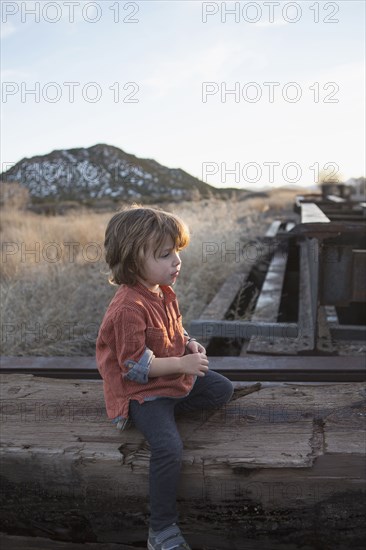 Caucasian boy sitting on wood outdoors