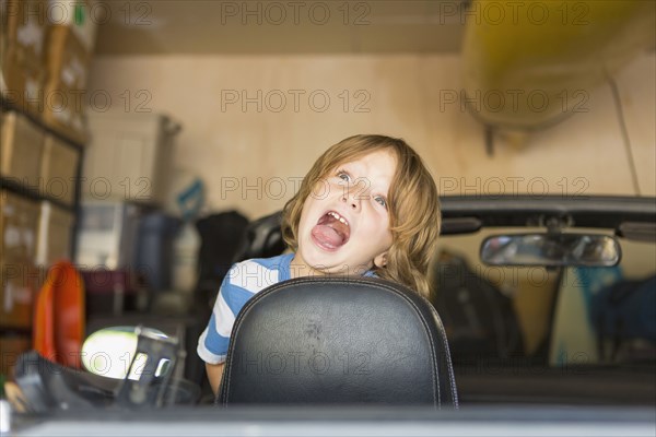 Caucasian boy making a face in convertible car