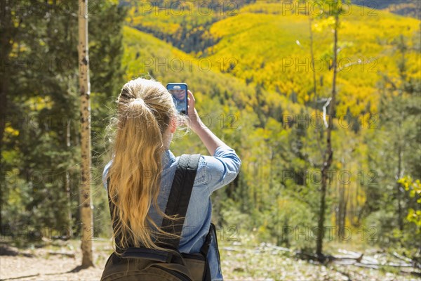 Caucasian girl photographing scenic view with cell phone