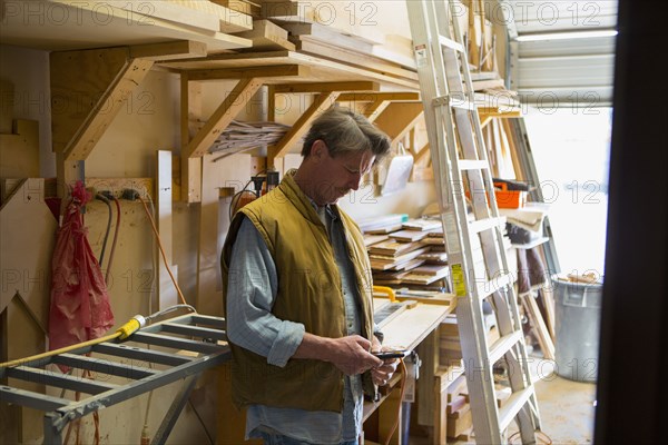 Caucasian carpenter texting on cell phone in workshop