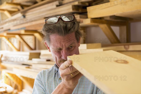 Caucasian carpenter eyeballing wooden plank in workshop
