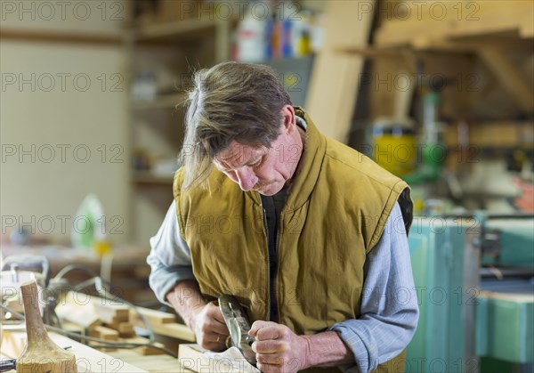 Caucasian carpenter sanding wood in workshop