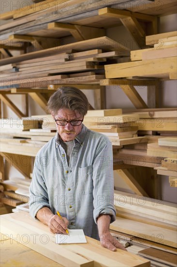 Caucasian carpenter writing on notepad in workshop