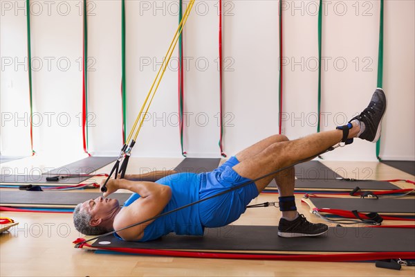 Mixed Race man using resistance bands in gymnasium