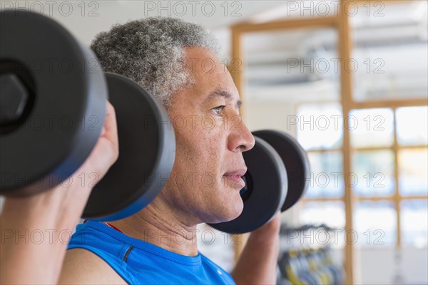 Mixed Race man lifting dumbbells in gymnasium