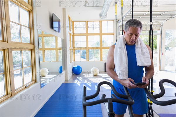Mixed Race man texting on cell phone in gymnasium