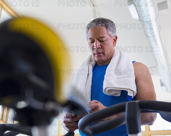 Mixed Race man texting on cell phone in gymnasium