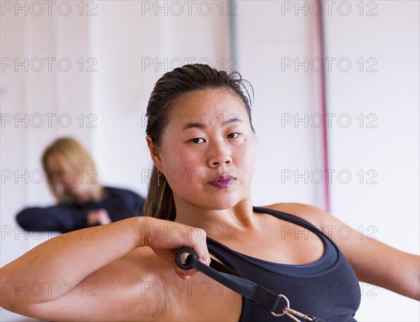 Portrait of Asian woman pulling handle in gymnasium