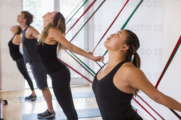 People pulling on resistance bands in gymnasium