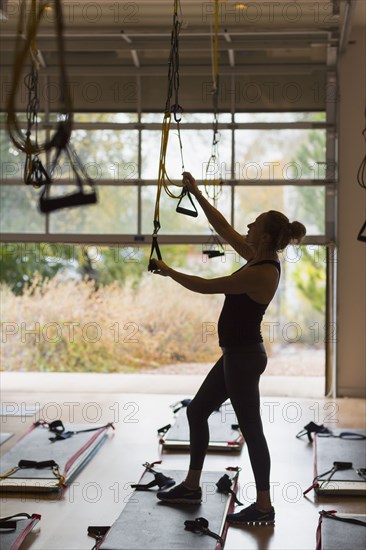 Caucasian woman adjusting resistance bands in gymnasium