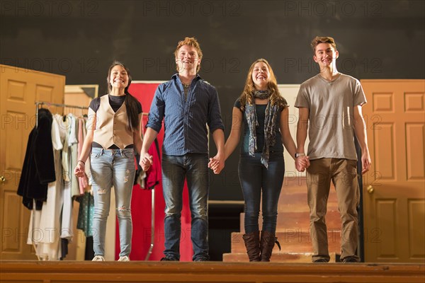 Students holding hands on stage