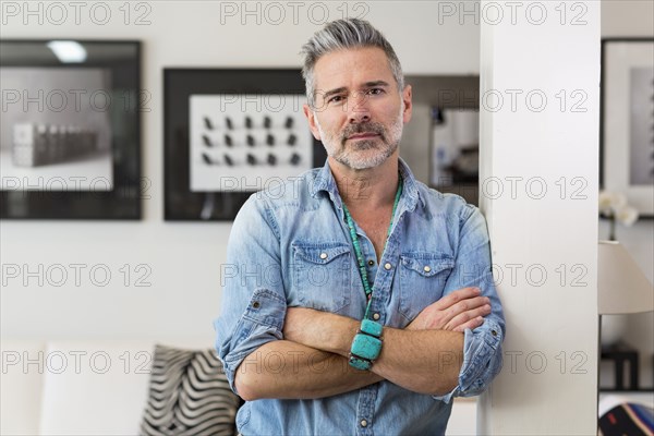 Caucasian man with arms crossed leaning on pillar