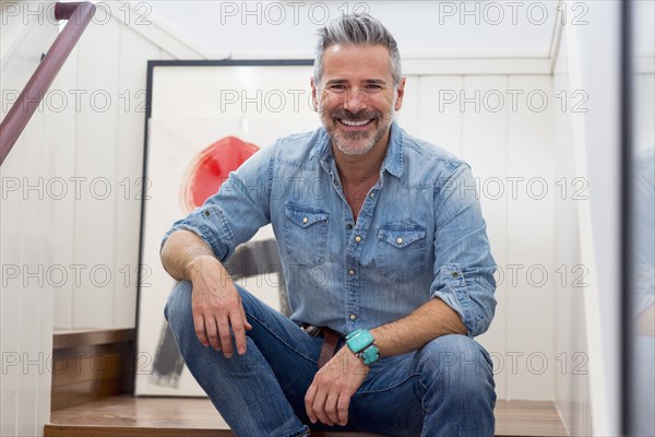 Smiling Caucasian man sitting on staircase