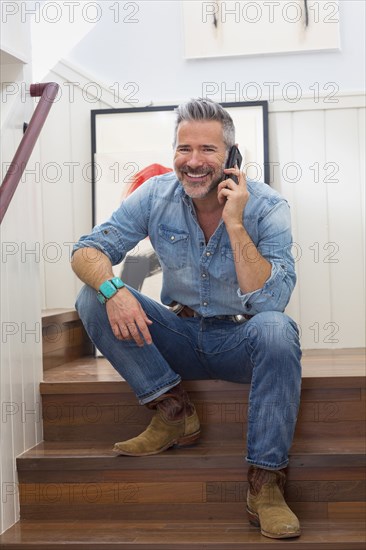 Caucasian man sitting on staircase talking on cell phone
