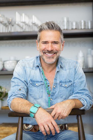 Smiling Caucasian man leaning on chair in store