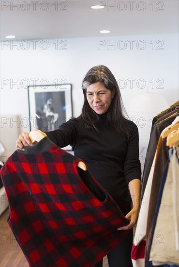 Hispanic woman examining plaid vest in store