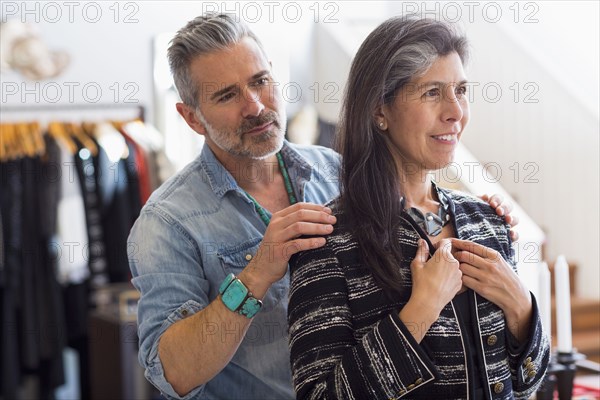 Man helping woman with jacket in store