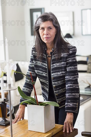 Serious Hispanic woman leaning over orchid