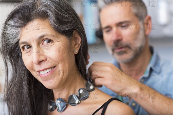 Man fastening necklace for woman