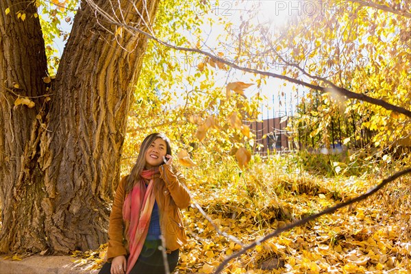 Asian woman talking on cell phone in autumn