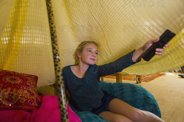 Caucasian girl using remote control in blanket fort