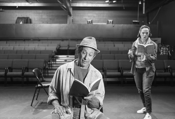 Caucasian actors rehearsing with scripts in theater