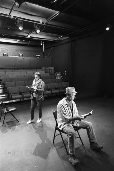 Caucasian actors rehearsing with scripts in theater