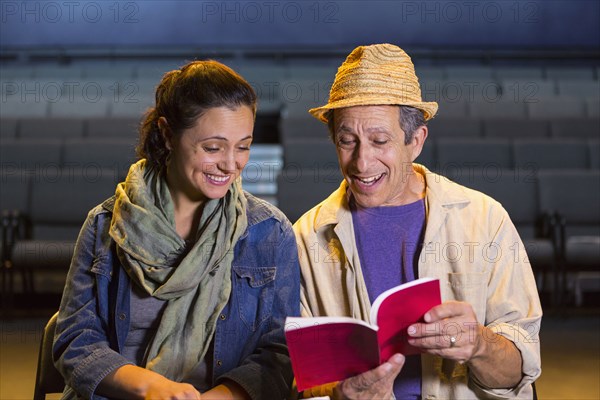 Caucasian actors rehearsing with script in theater