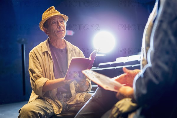 Caucasian actors rehearsing with scripts in theater