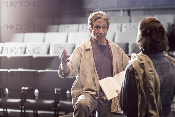 Caucasian actors rehearsing with script in theater