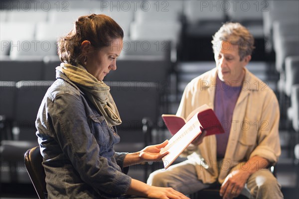 Caucasian actors rehearsing with scripts in theater