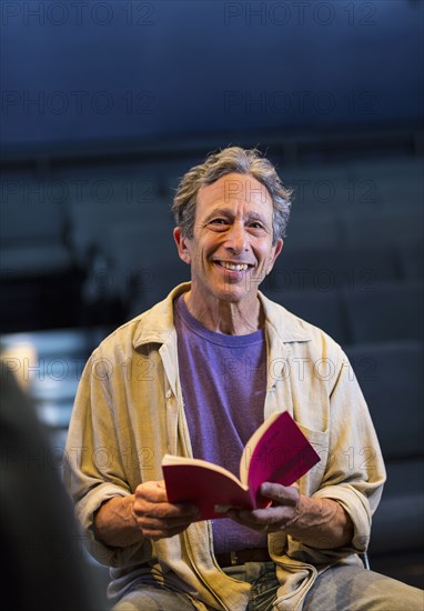 Portrait of smiling Caucasian actor holding script in theater