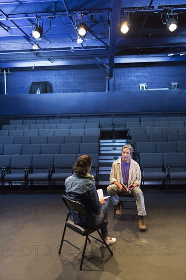 Caucasian actors rehearsing with scripts in theater