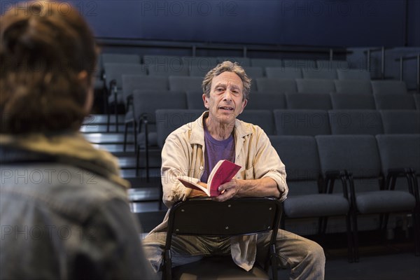 Caucasian actors rehearsing with script in theater