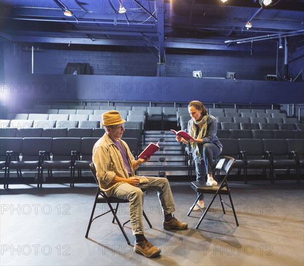 Caucasian actors rehearsing with scripts in theater