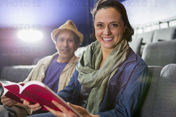 Portrait of Caucasian actors sitting in audience with scripts in theater