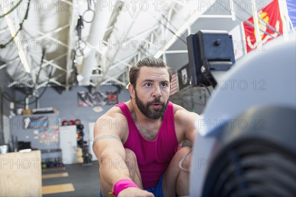 Mixed Race man using rowing machine in gymnasium