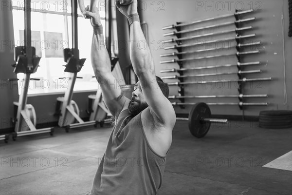 Mixed Race man working out with rings in gymnasium