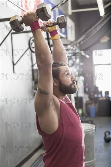 Mixed Race man lifting dumbbells in gymnasium