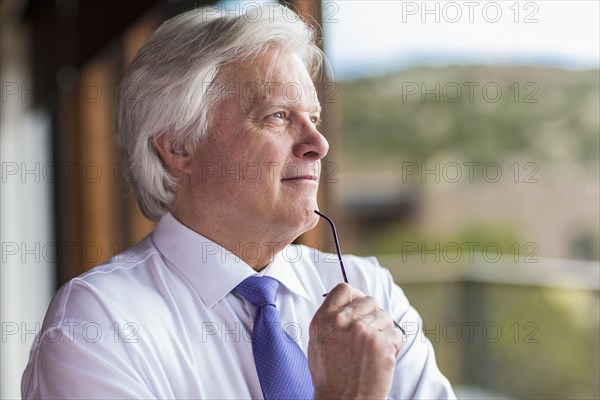 Pensive Caucasian businessman holding eyeglasses