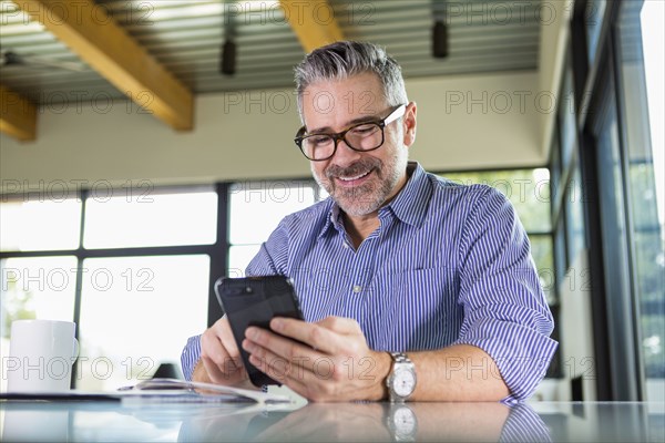 Caucasian man texting on cell phone at table