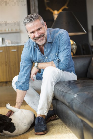 Caucasian man sitting on sofa petting dog