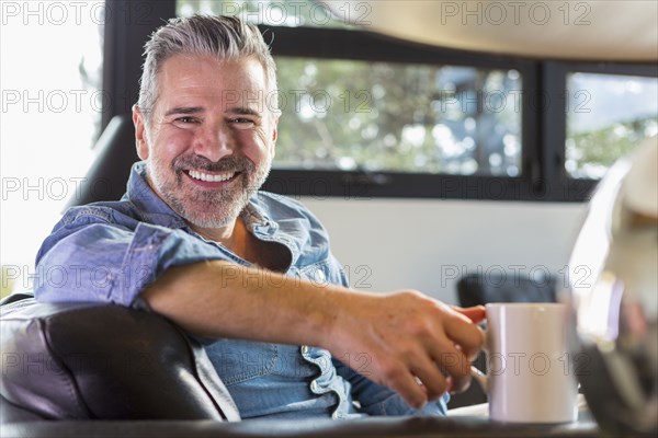 Caucasian man sitting on sofa and drinking coffee